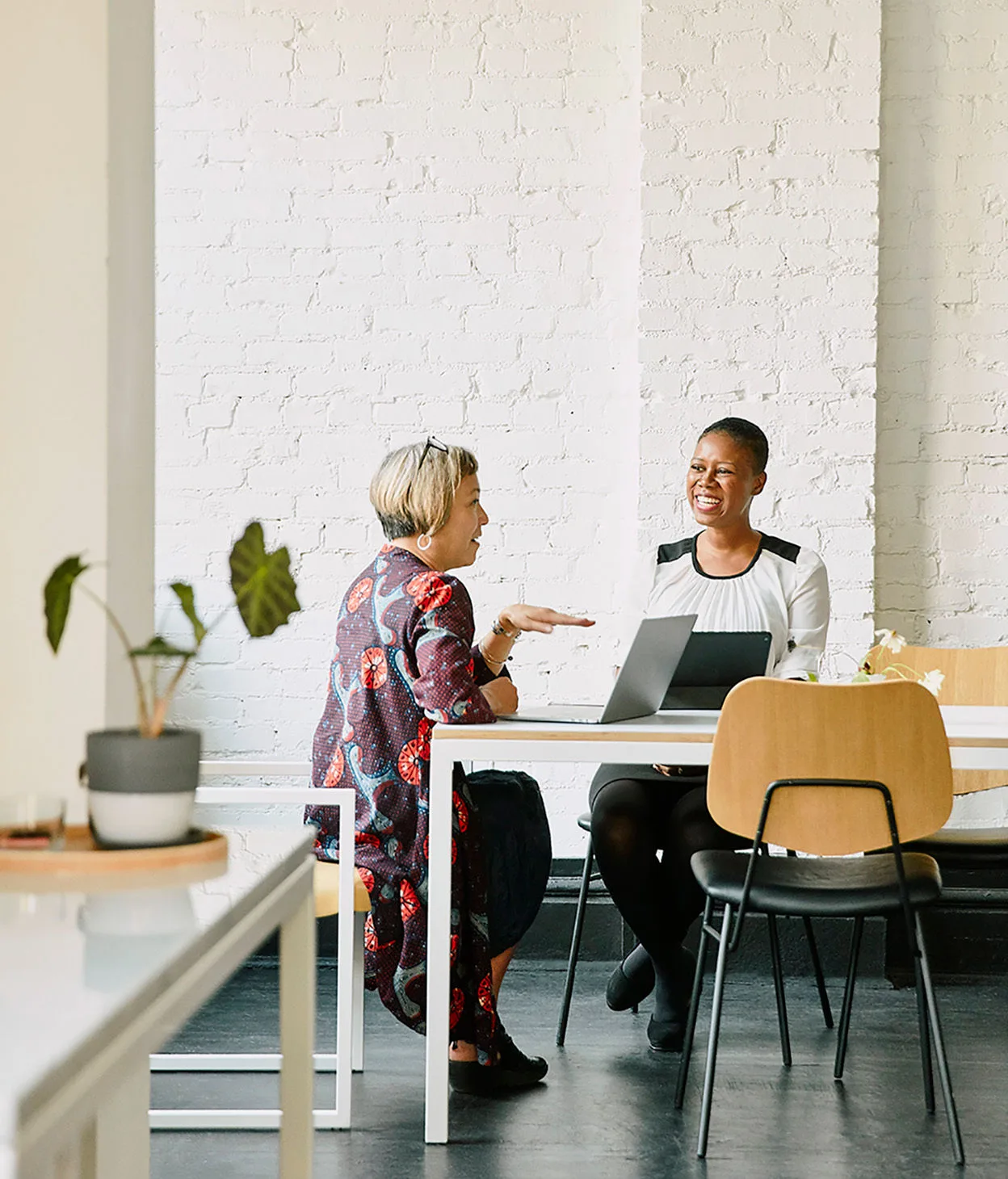 Smiling businesswomen discuss in an office conference room.